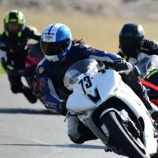 Motorcyclists cornering with ample space for clean lines and coach guidance